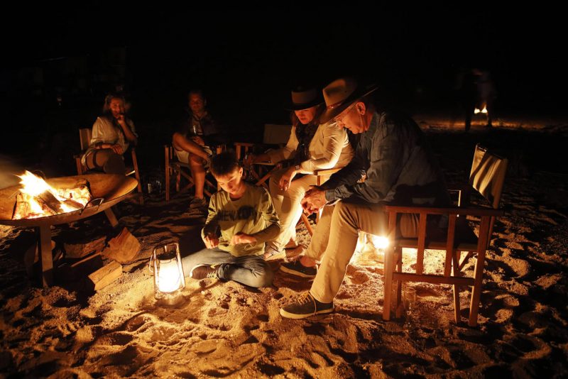 A group of friends sitting around a campfire having a good chat